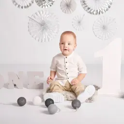 Urocza sesja zdjęciowa na roczek. Chłopiec w białej koszuli siedzi obok liter "ONE" i dużej cyfry "1".