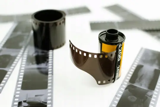 Rolka filmu i wywołanie zdjęć z kliszy. W tle inne klisze i rolka filmu.
