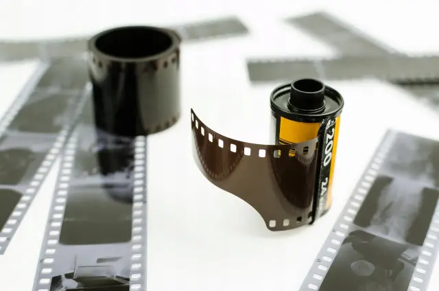 Rolka filmu i wywołanie zdjęć z kliszy. W tle inne klisze i rolka filmu.